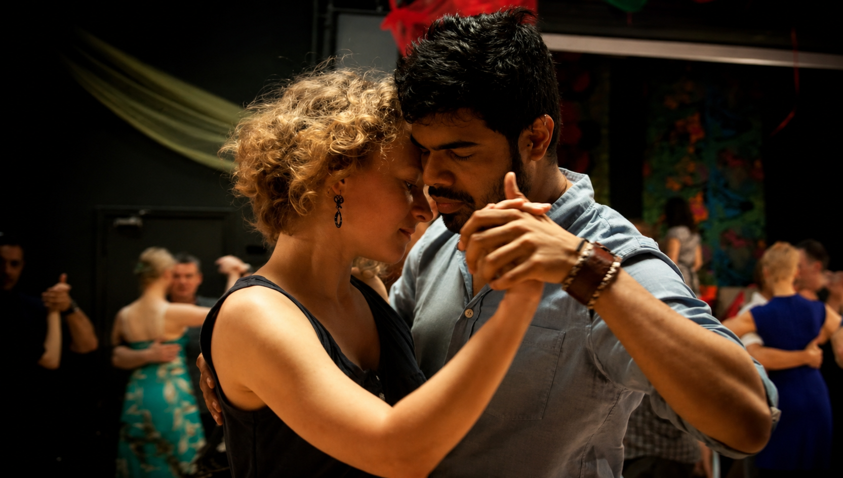 Bynoi Desouza in a close embrace tango hold, dancing among other couples.