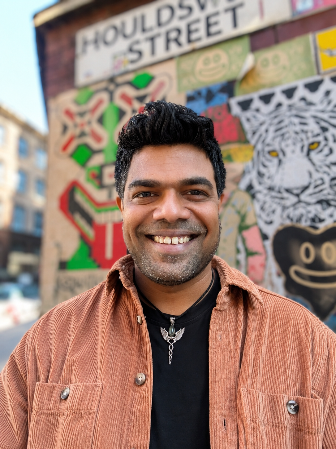 Bynoi Desouza, standing in front of the Houldsworth Street mural in Manchester.